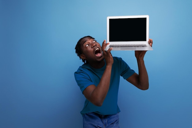 Amerikanischer junger männlicher brünetter Berater im lässigen T-Shirt zeigt einen Laptop für Werbung