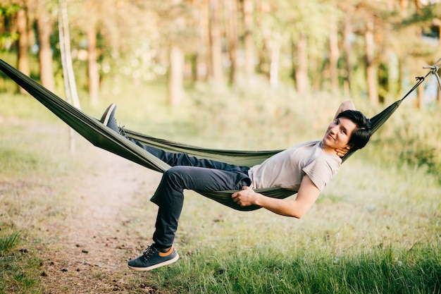 Amerikanischer junger Mann Narive, der in der Hängematte an der Natur am sonnigen Sommertag sich entspannt.