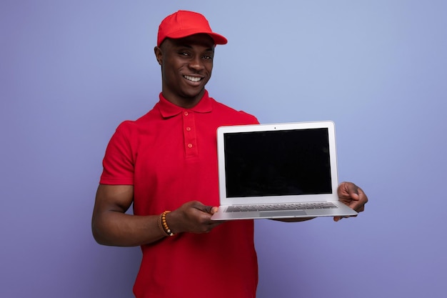 Amerikanischer Servicemitarbeiter mit roter Mütze und T-Shirt, der einen Laptop mit Modell hält