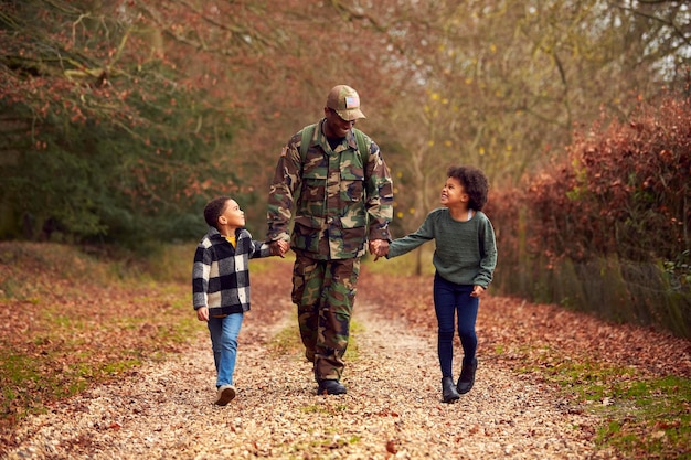 Amerikanischer Soldat in Uniform, der auf Urlaub nach Hause zurückkehrt, um die Hände der Familie mit zwei Kindern zu halten