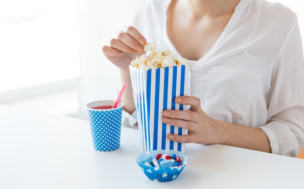 amerikanischer unabhängigkeitstag, feier, patriotismus und feiertagskonzept - nahaufnahme einer frau, die popcorn mit getränken und süßigkeiten auf der party am 4. juli isst