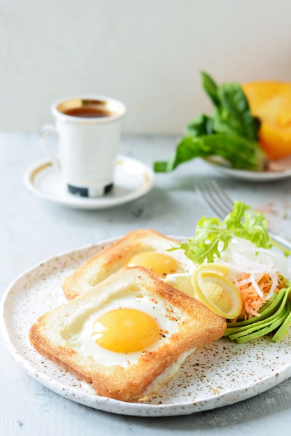 Amerikanisches Frühstück auf einem Teller mit Spiegeleiern in Toast, mit Tomaten, frischem Daikon, Karotten, Rucola und Espresso. Spiegelei für traditionelles Frühstück Nahaufnahme schießen