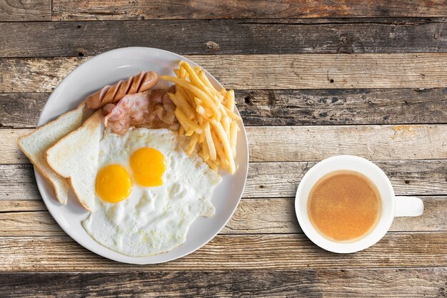 Amerikanisches Frühstück mit durcheinandergemischten Eiern und Kaffeetasse auf Holztischhintergrund