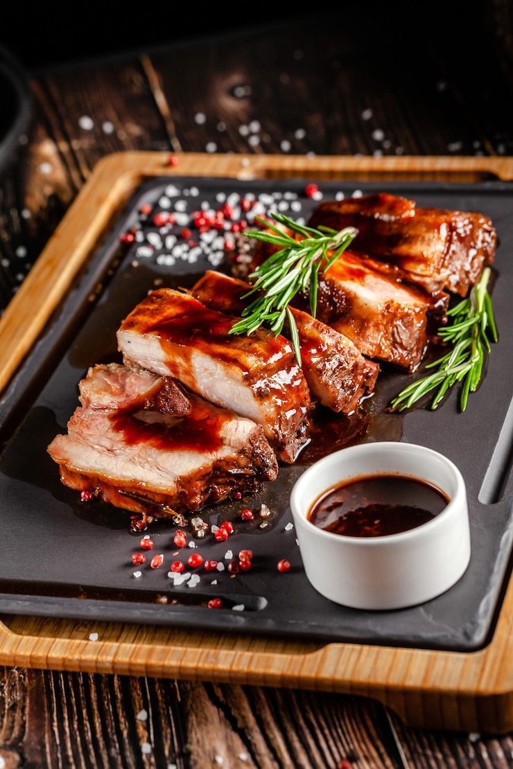 Amerikanisches Lebensmittelkonzept. Gegrillte Schweinerippchen mit gegrillter Sauce, mit Rauch, Gewürzen und Rosmarin. Hintergrundbild. Speicherplatz kopieren