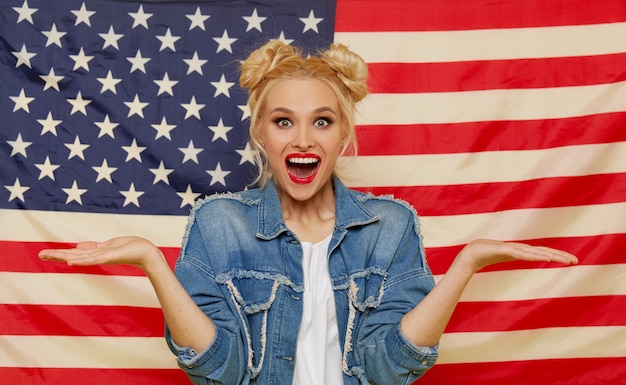 Amerikanisches Mädchen. Porträt der glücklichen jungen überraschten Frau auf USA-Flaggenhintergrund.