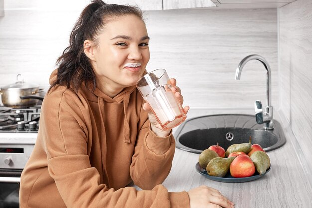 Una amigable niña bebe un batido de manzana, yogur y pera recién hecho de un vaso