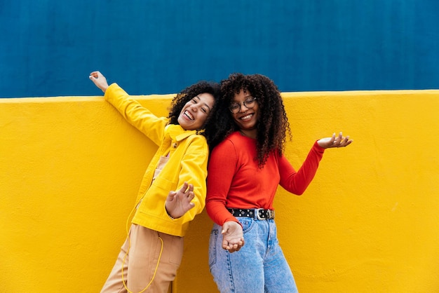 Amigas a desfrutar contra a parede amarela