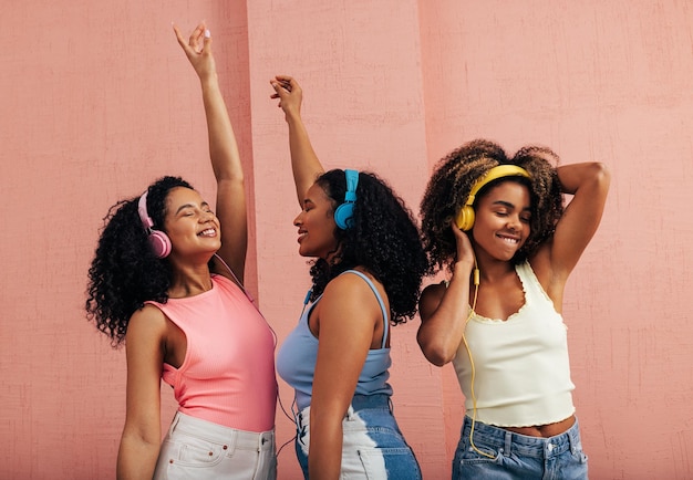 Amigas a desfrutar de música contra a parede.