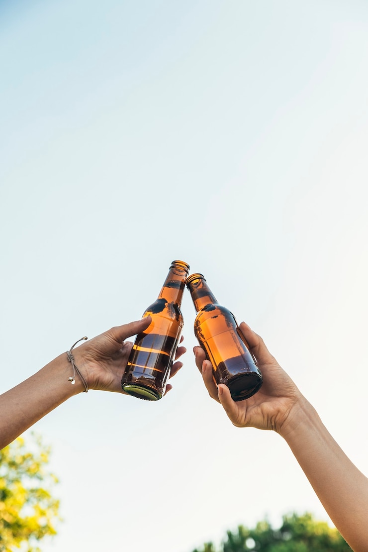 Foto amigas aclama el tintineo de botellas de cerveza en las manos en el parque.