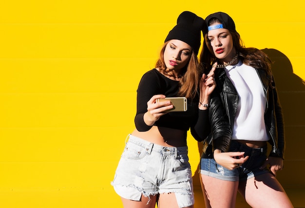 Las amigas adolescentes al aire libre hacen selfie en un teléfono.