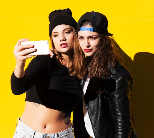 Las amigas adolescentes al aire libre hacen selfie en un teléfono.