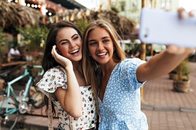 Amigas alegres de buen humor toman selfie al aire libre y sonríen