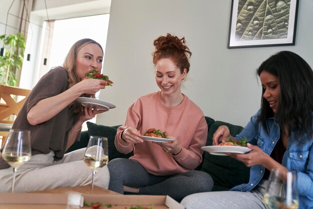 Amigas alegres comiendo en casa.