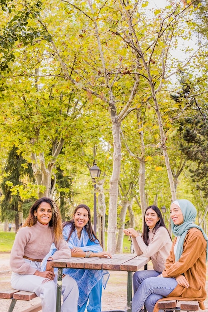 Foto amigas alegres sentadas en el parque