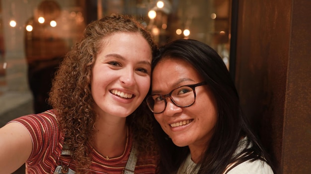 Amigas Amigas bastante multirraciais tirando selfie com smartphone Retrato de estilo de vida de duas jovens positivas tirando uma foto