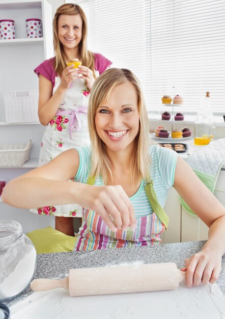 Amigas animadas hornear muffins sonriendo a la cámara