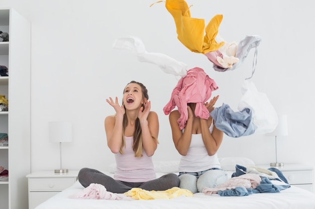 Amigas bonitas con ropa en la cama