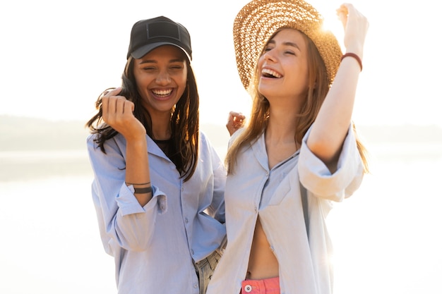 Foto amigas caminando por la playa y riendo en un día de verano.