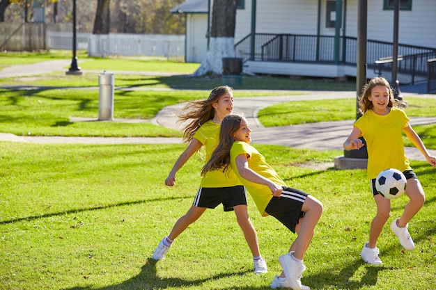 Amigas chicas adolescentes jugando fútbol soccer en un parque