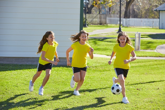 Foto amigas chicas adolescentes jugando fútbol soccer en un parque