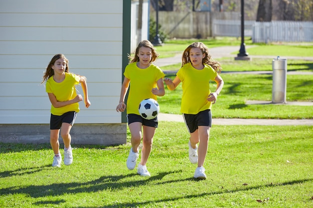 Amigas chicas adolescentes jugando fútbol soccer en un parque