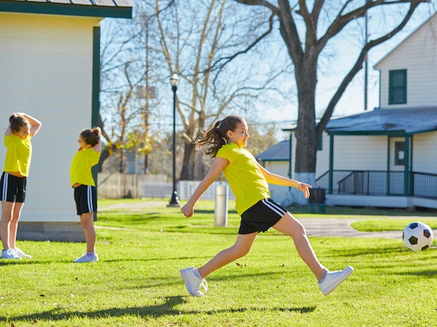 Amigas chicas adolescentes jugando fútbol soccer en un parque