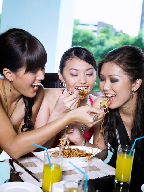 Foto amigas comiendo espagueti mientras están sentadas en un restaurante