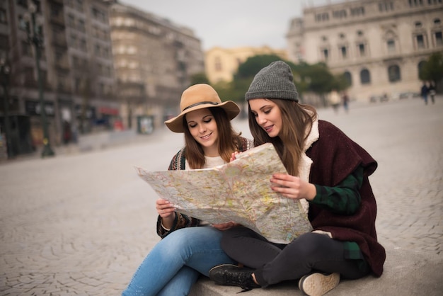 Amigas consultando um mapa da cidade no inverno