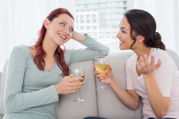 Amigas con copas de vino charlando en casa