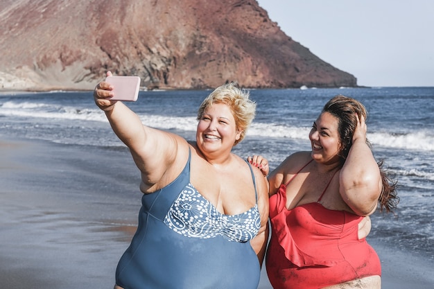 Amigas con curvas tomando selfie en la playa
