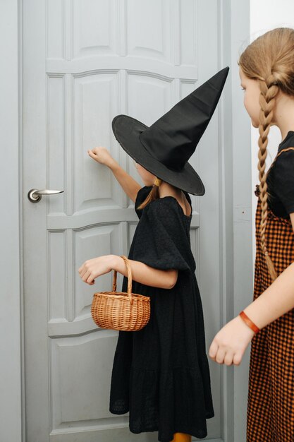 Amigas em trajes de halloween batendo na porta de doces ou travessuras