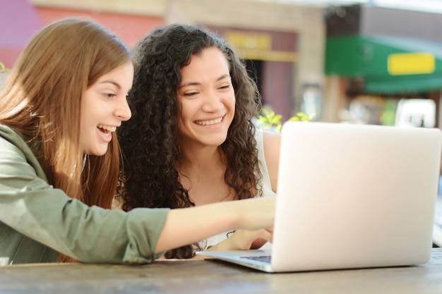 Amigas estudiando con una computadora portátil en una cafetería.