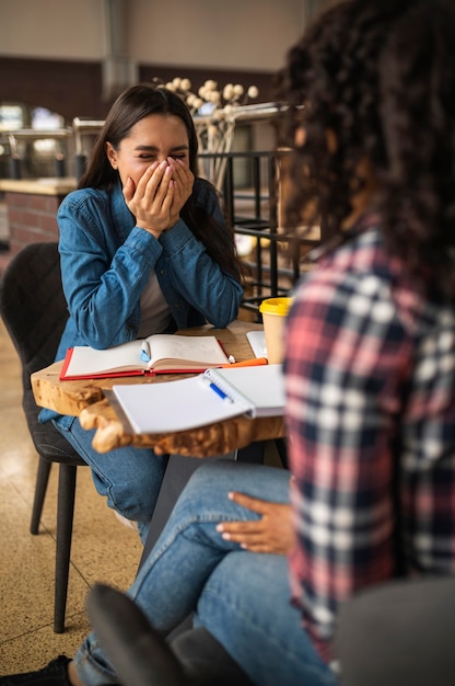 Amigas felices haciendo los deberes juntos en el café