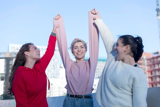 Amigas felizes de pé no terraço do edifício contra o céu