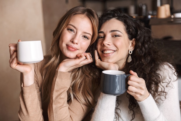 Amigas felizes sentadas em um café conversando e bebendo chá ou café