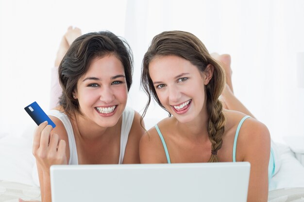 Amigas haciendo compras en línea en la cama