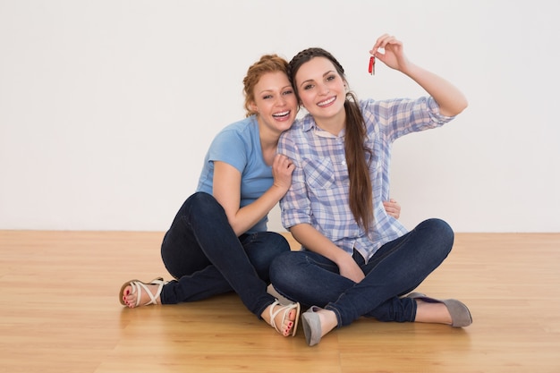 Amigas con las llaves de la casa sentados en el suelo