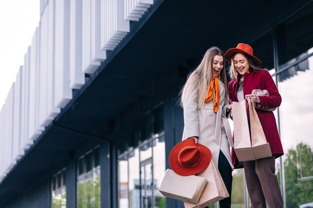 Amigas mostrando compras dentro de sacolas depois das compras