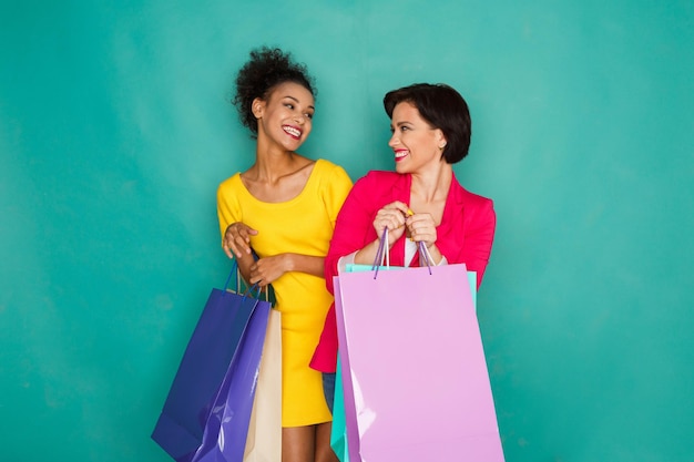 Amigas multiétnicas felices con bolsas de la compra.