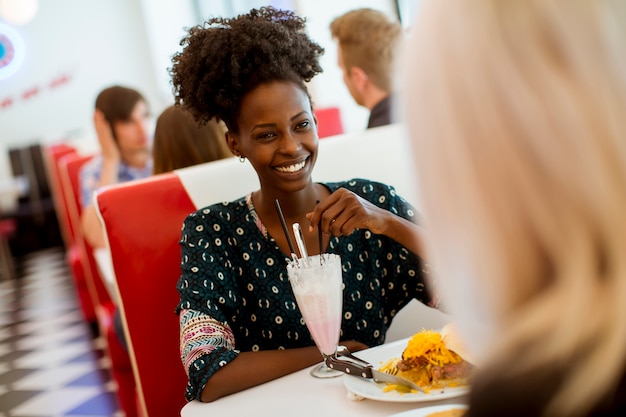 Amigas multirraciales comiendo comida rápida en una mesa en el restaurante