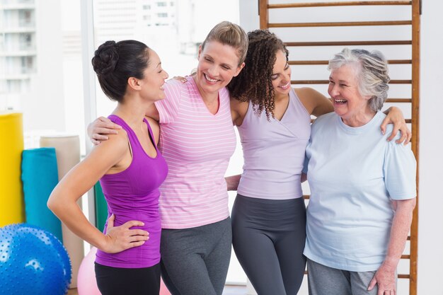 Amigas de pie brazos alrededor en el gimnasio