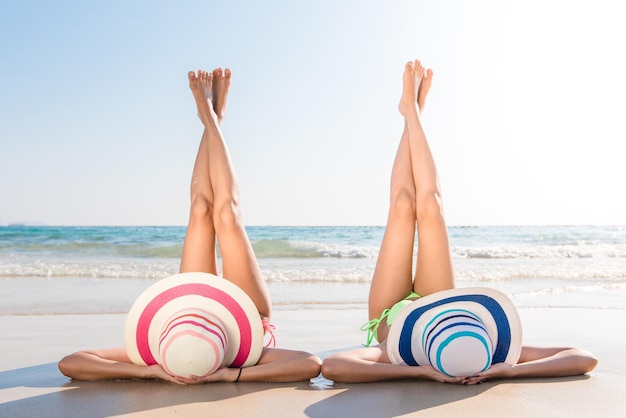 Foto amigas con las piernas levantadas acostadas en la orilla en la playa durante un día soleado