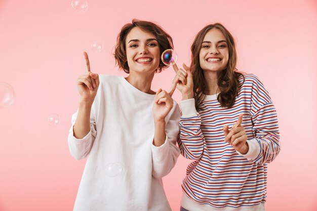 Amigas posando aisladas sobre pompas de jabón.