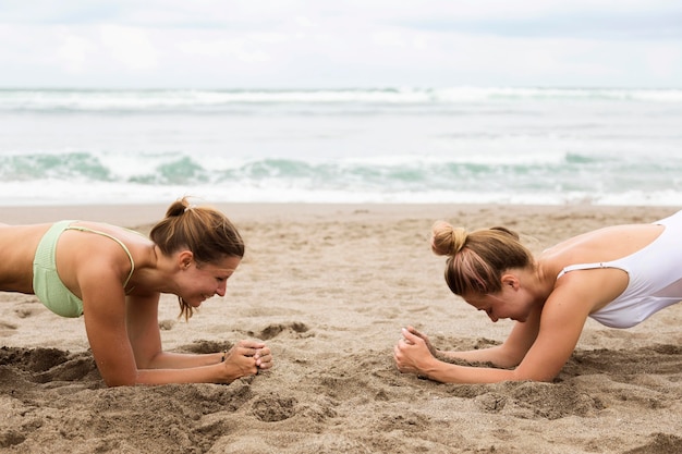 Foto amigas practicando entarimado en la playa