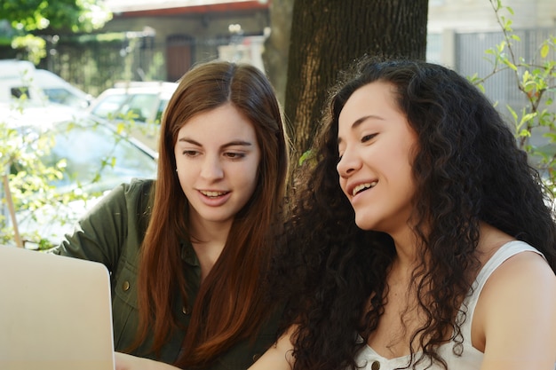 Amigas que estudian con un ordenador portátil en una cafetería.