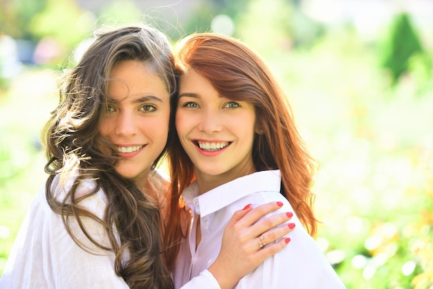 Amigas rindo e se abraçando ao ar livre, duas mulheres se abraçando no conceito de abraço de campo verde
