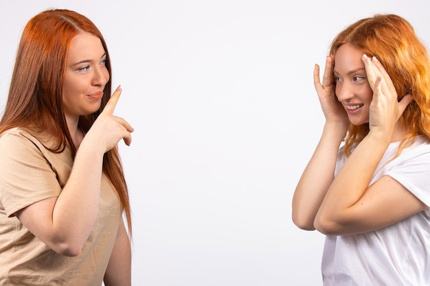 Amigas ruivas fazem caretas e paqueram se divertindo, foto na parede branca com espaço em branco