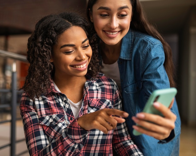 Foto amigas con smartphone en el café