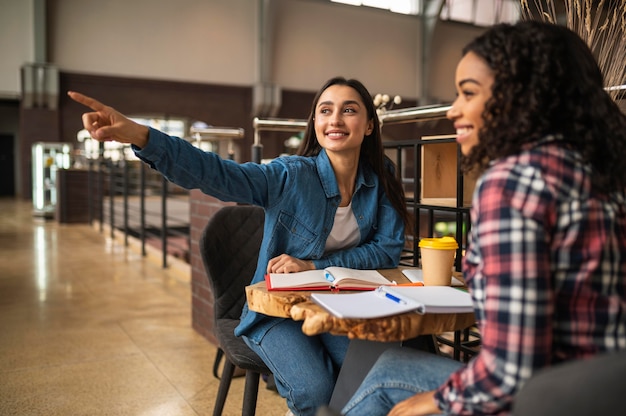 Foto amigas sonrientes juntos en el café haciendo los deberes