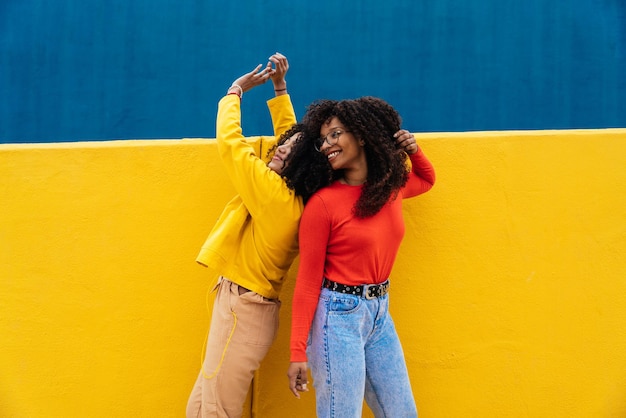 Amigas sorridente dançando contra a parede